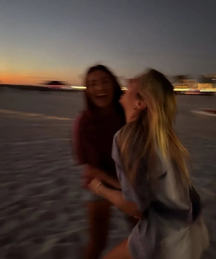 Deux amies qui rient sur une plage au crépuscule, image floue