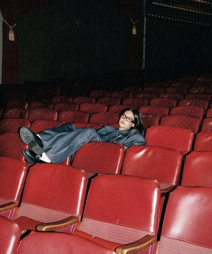 Jeune femme allongée sur les sièges rouges d'un vieux cinéma