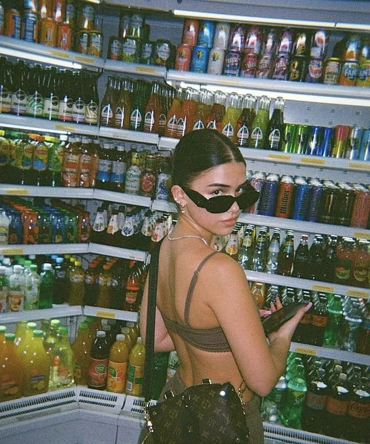 Jeune femme en lunettes de soleil devant les boissons fraîches