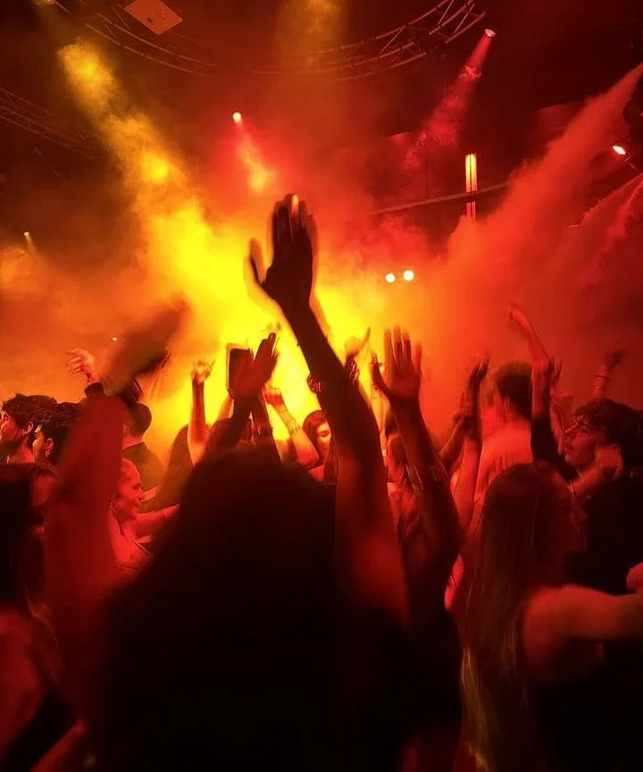 Mains levées dans la fumée rouge d'une soirée